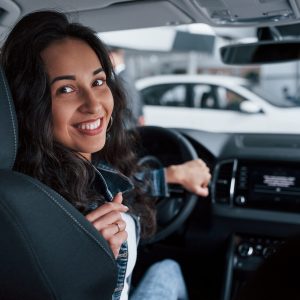 Moving backwards. ute girl with black hair trying her brand new expensive car in the automobile salon.